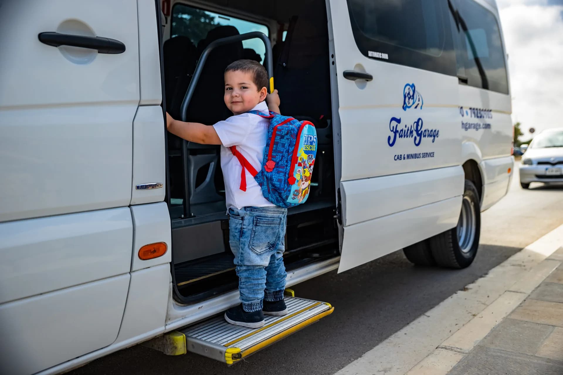 A child boarding a Faith Garage school minibus